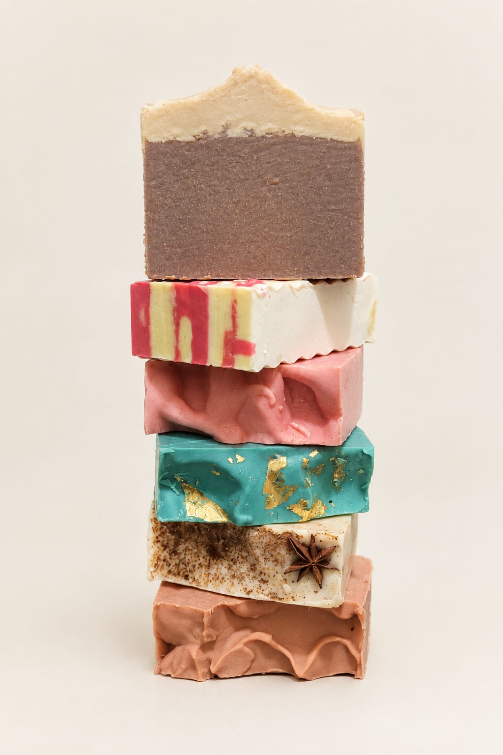 A colourful stack of handcrafted seasonal soaps, including candy cane swirls and green festive bars with gold accents